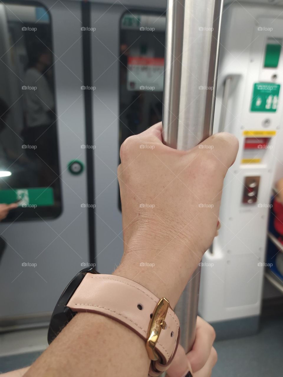 A hand hold a bar in the subway. In the background the doors are closed.