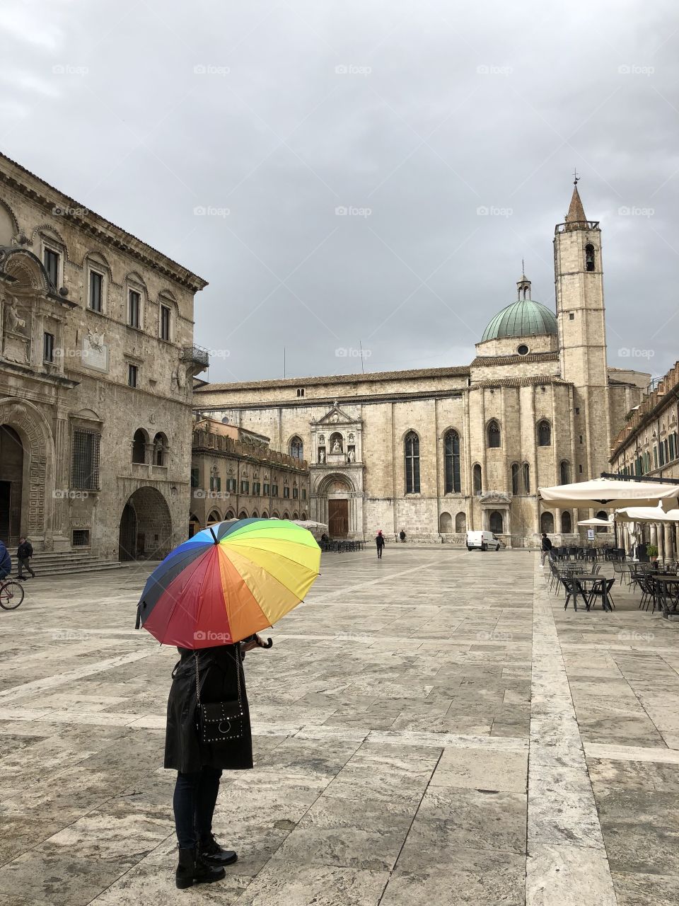 Woman in the middle of the square with a multicolored umbrella