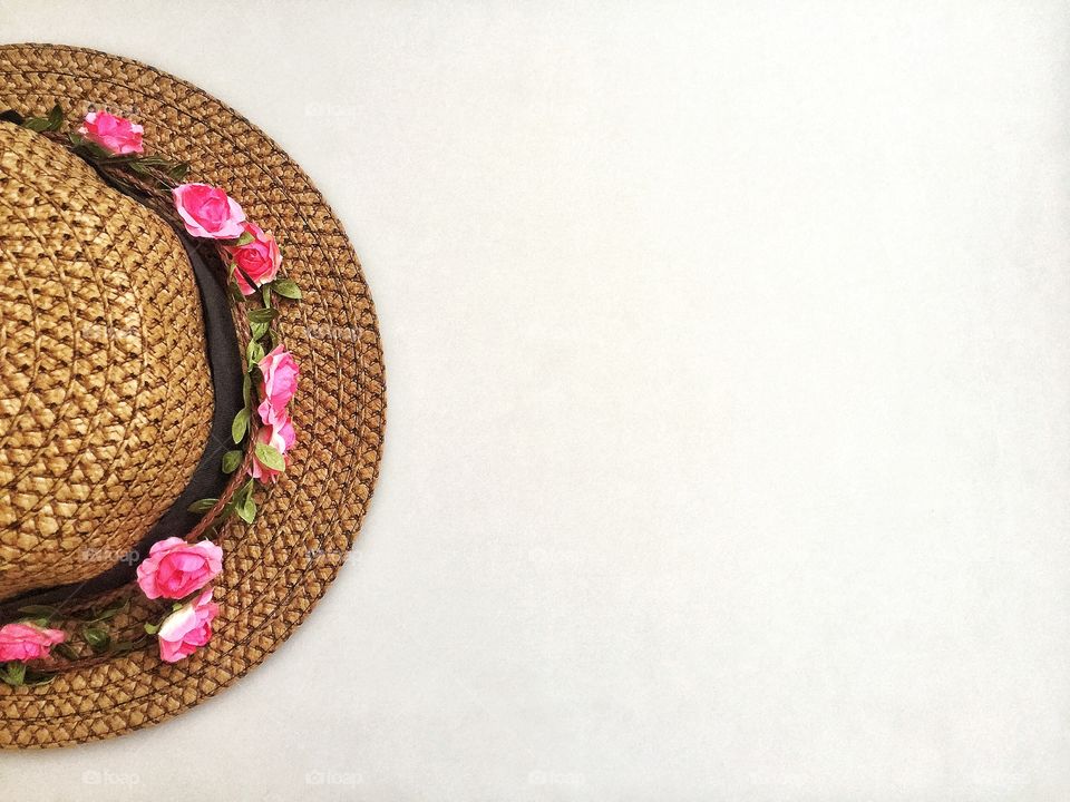 Hat and pink flowers on gray background 