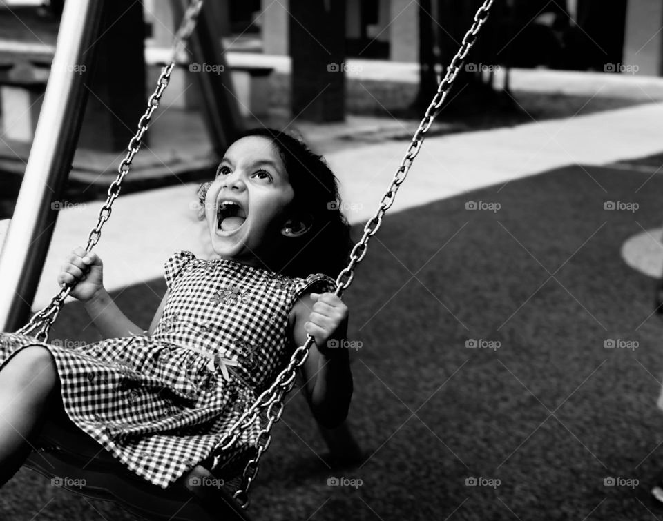 A baby girl screaming while swinging it looks funny 