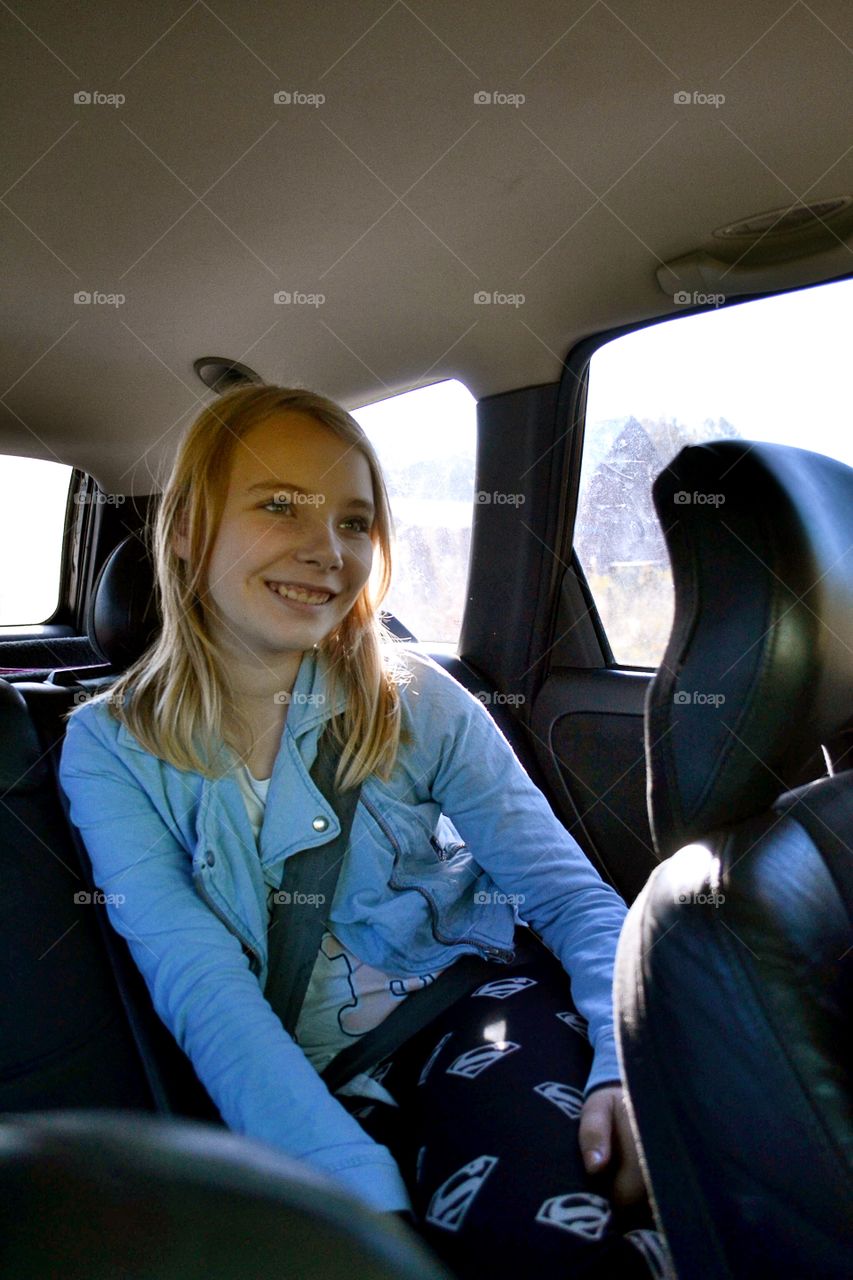 Girl in the backseat of a car smiling