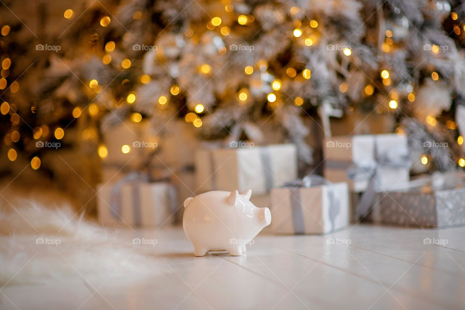 piggy bank with 100 dollars banknote in festive New Year atmosphere of scenery.  Magical bokeh with Christmas tree and bright lights.