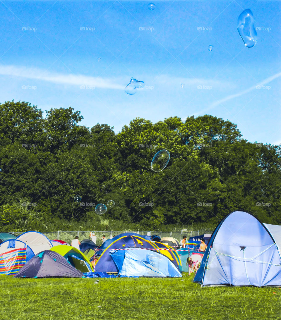 Bubbles fly over a group on tents into the blue sky at a summer festival