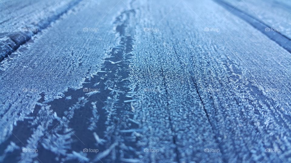 Ice cryatals on the surface of a wooden picnic table after a heavy frost.