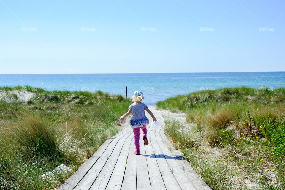 Little girl is running to the beach to pick seashells in Falsterbo in Sweden.