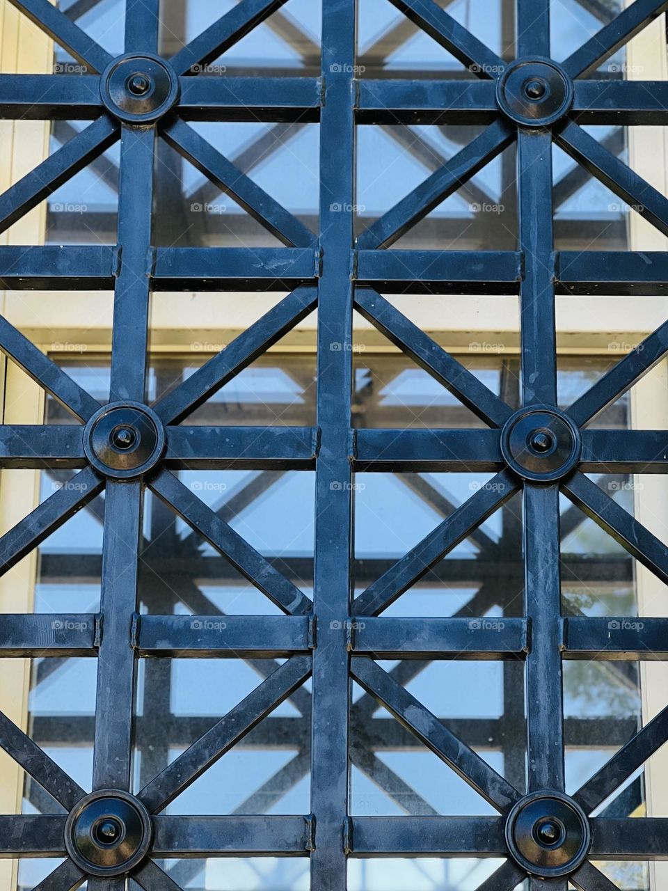 Triangle pattern on decorative iron window covering. Pattern is also reflected underneath in the window panes.