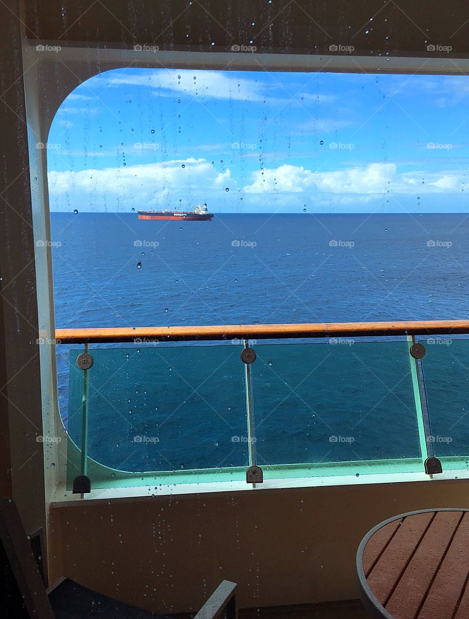 A tanker out in the distance.  View from a window looking out over the balcony on a cruise ship. 