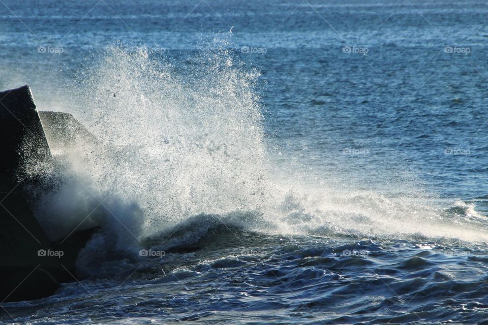 Stormy waves in the blue atlantic ocean breaking on the rock