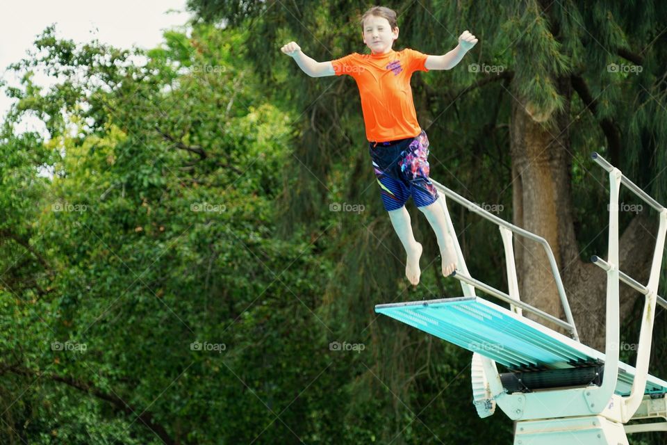 Young Boy Jumping Off A Diving Board