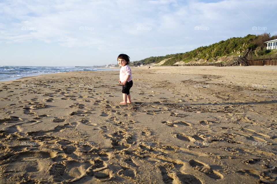 little girl running happy barefoot on the beach