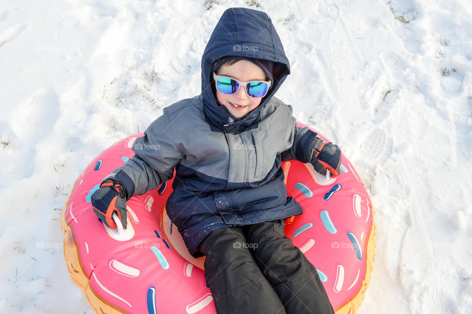 Young boy happily riding a snow tube