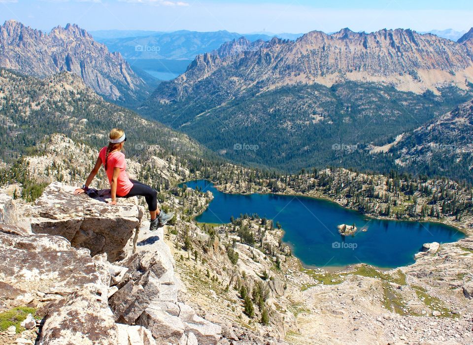 Woman in pink sits on a rock overlooking a beautiful mountain lake