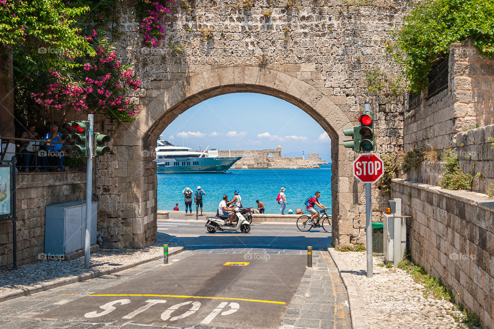 Scooter, bicycle or perhaps luxurious yacht. That's the way to sightseeing. Medieval gateway to Old Port in Rhodes Town. Island of Rhodes. Greece. Europe.