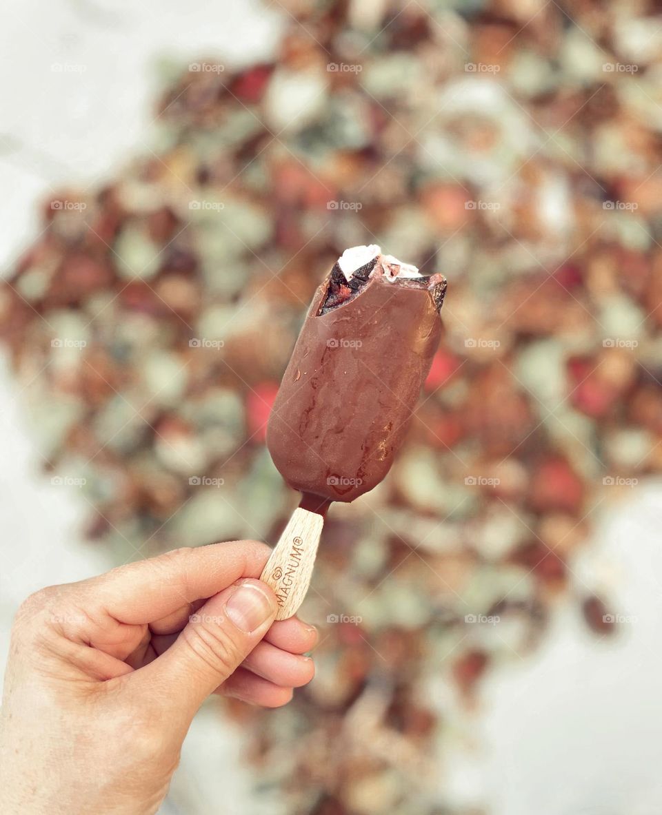 Woman’s hand holding ice cream bar, moments of happiness eating ice cream outside, Magnum ice cream bar, eating ice cream outside, happily eating ice cream 