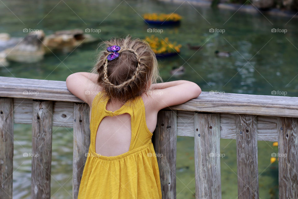 Beautiful little girl watching a lake