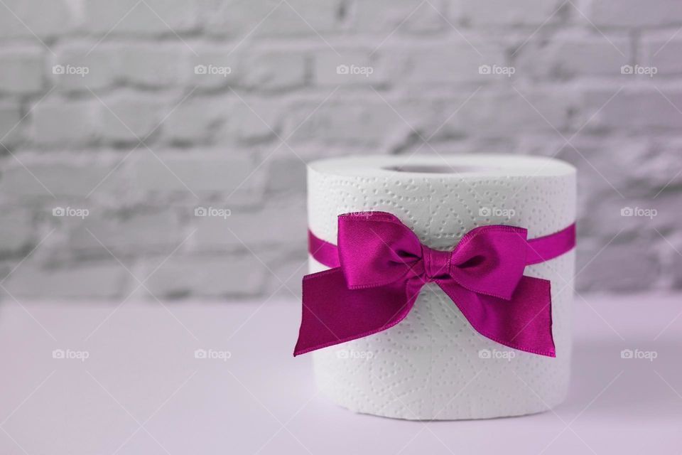 Toilet paper with pink bow on the white background