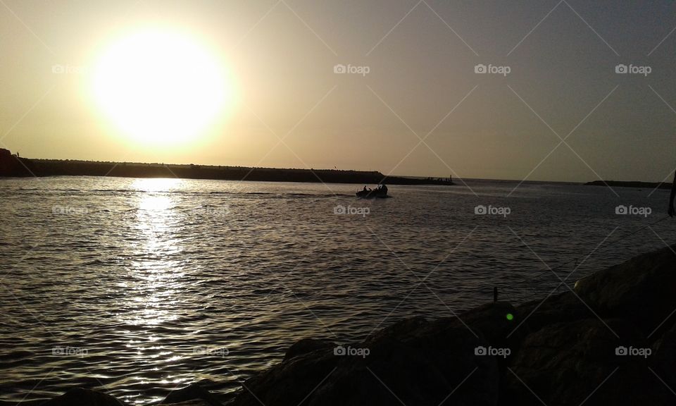 a fishing boat that leaves off the sea at sunset