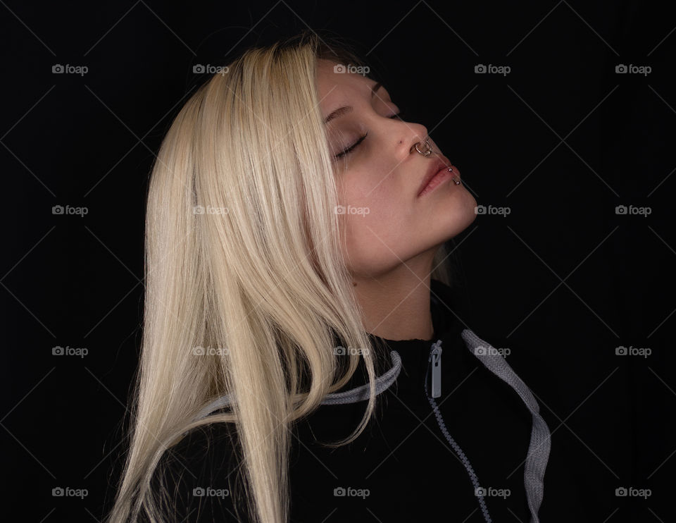 portrait of beautiful young woman blonde hair loose with eyes closed and chin raised background ne