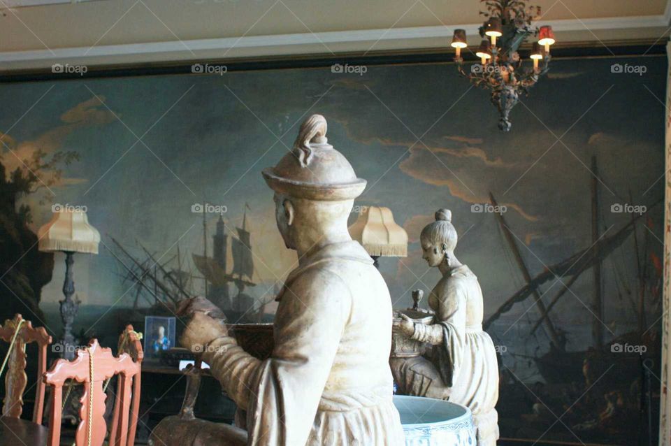 Asian sculptures figures overlooking mural in vintage mansion