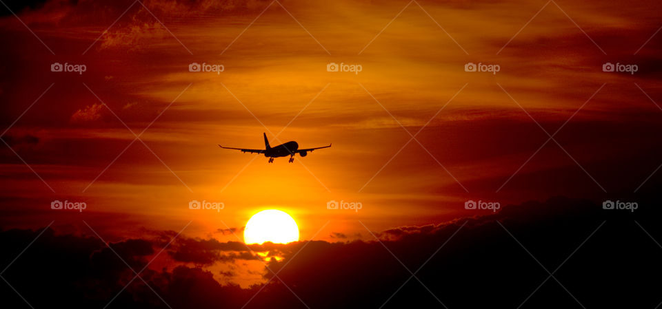 Sunset over Nairobi airport in Africa. A plane takes off from the runway and flying into the sunset.