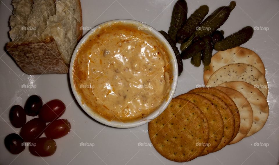 Appetizer Plate. crackers, bread, pickles and grapes with a hot cheese dip