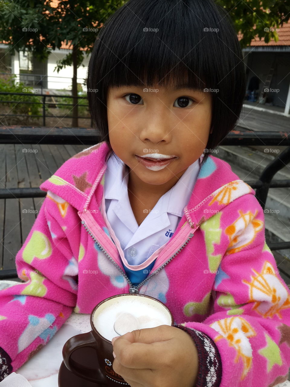 Cute Asian girl drinking creamy hot chocolate.