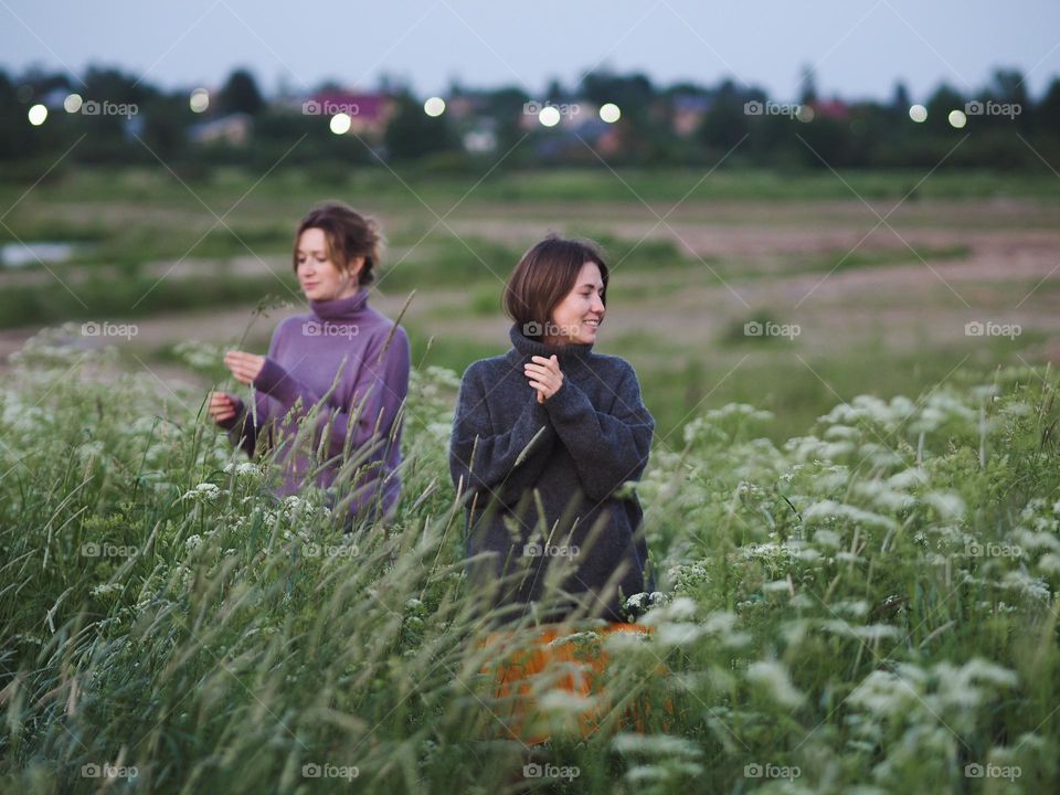 Two young beautiful woman’s walking in green field on a summer day, portrait of woman 