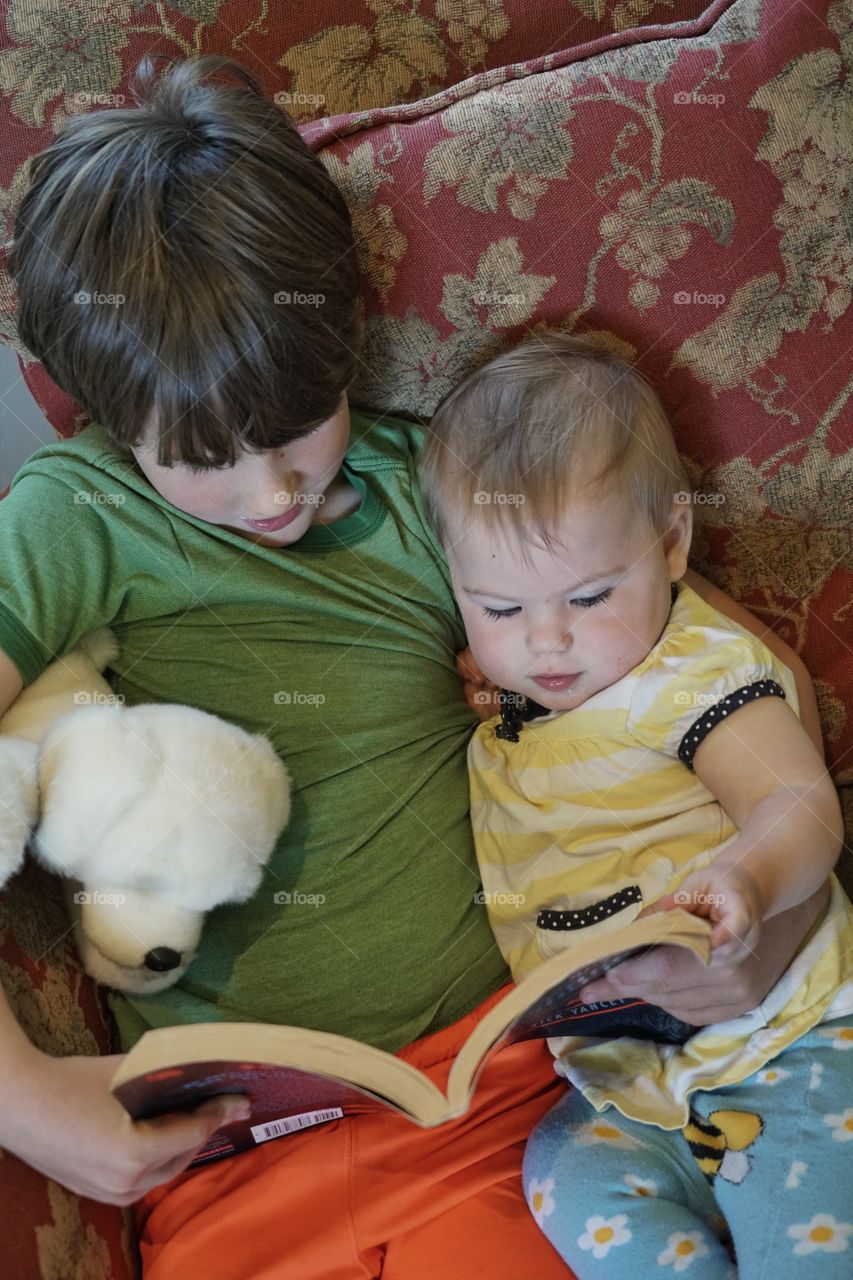 Big Brother Reading To His Baby Sister