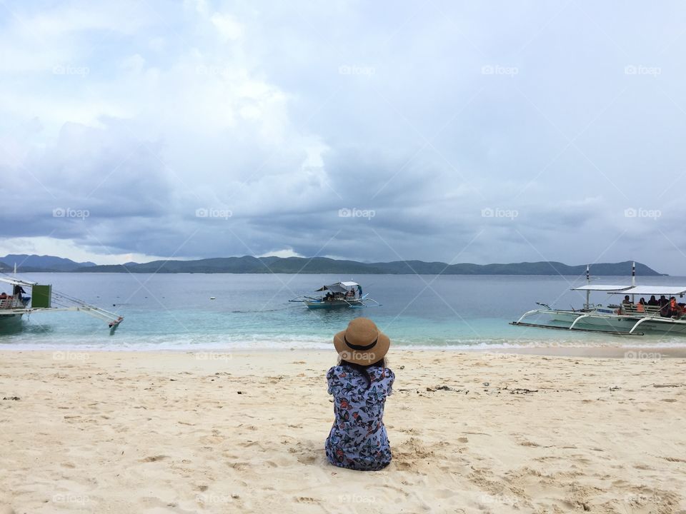 Woman sitting on white sand beach