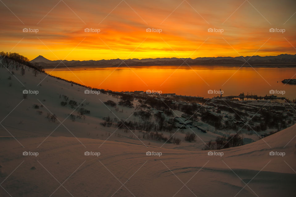 Golden sunset in Kamchatka.  Avacha Bay of the Pacific Ocean is illuminated by sunset light, and in the background you can see Vilyuchinsky volcano