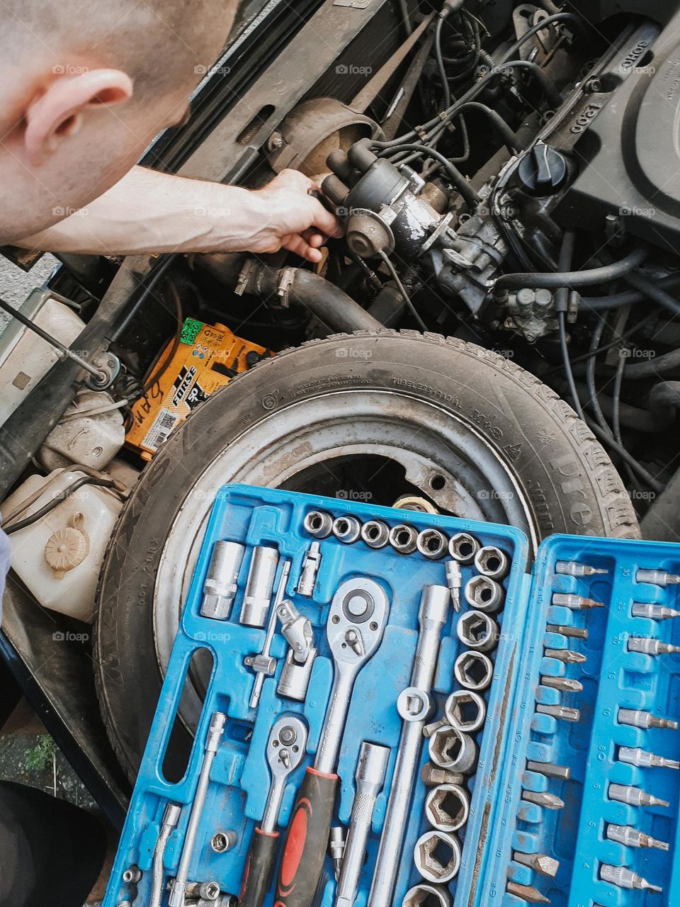 Photo of the moment of repairing a car and a work box with mechanic's tools