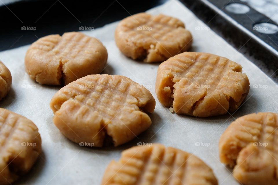 Close up of raw American peanut butter cookies on a baking sheet lined with baking paper