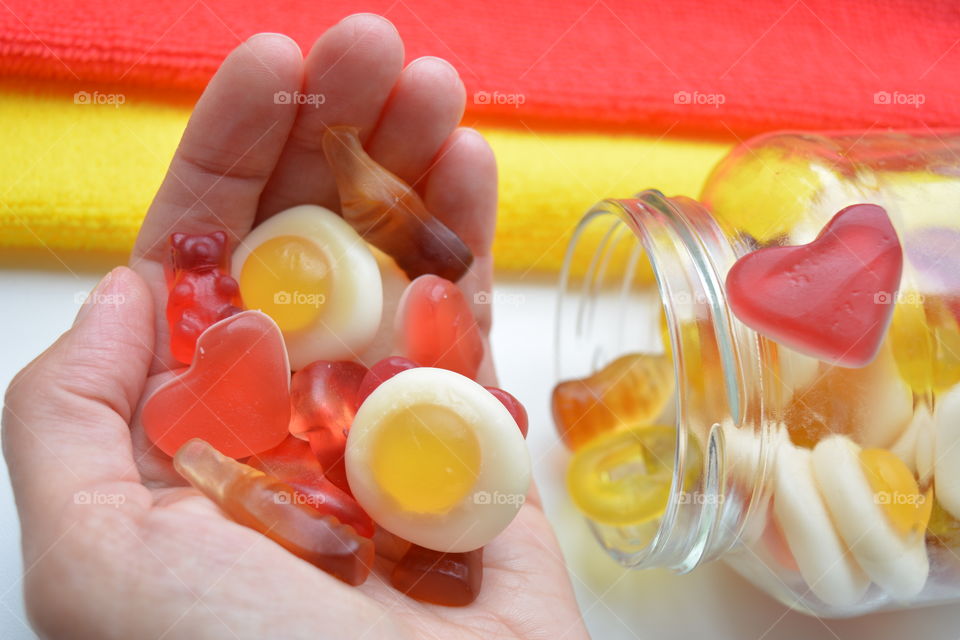 gelatin candy in the hand and jar sweets red and yellow background