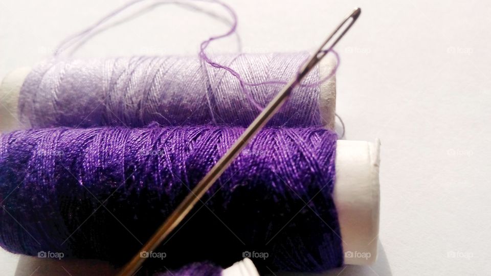 Close up of thred and needle, in shades of purple. Purple thing for sewing