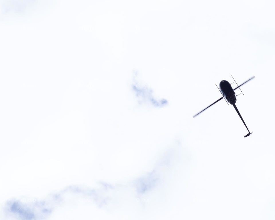 Helicopter flying overhead on a bright, cloudy day