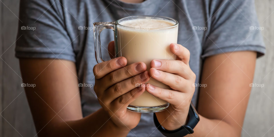 Closeup view of child's hands holding a cup with baked fermented milk. Healthy lifestyle concept.