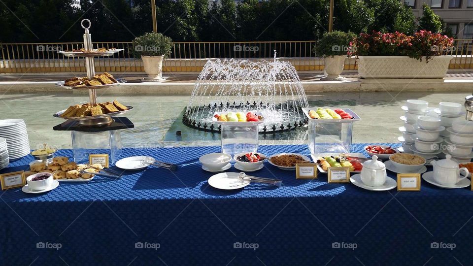 Sunny brunch on blue table with fountain