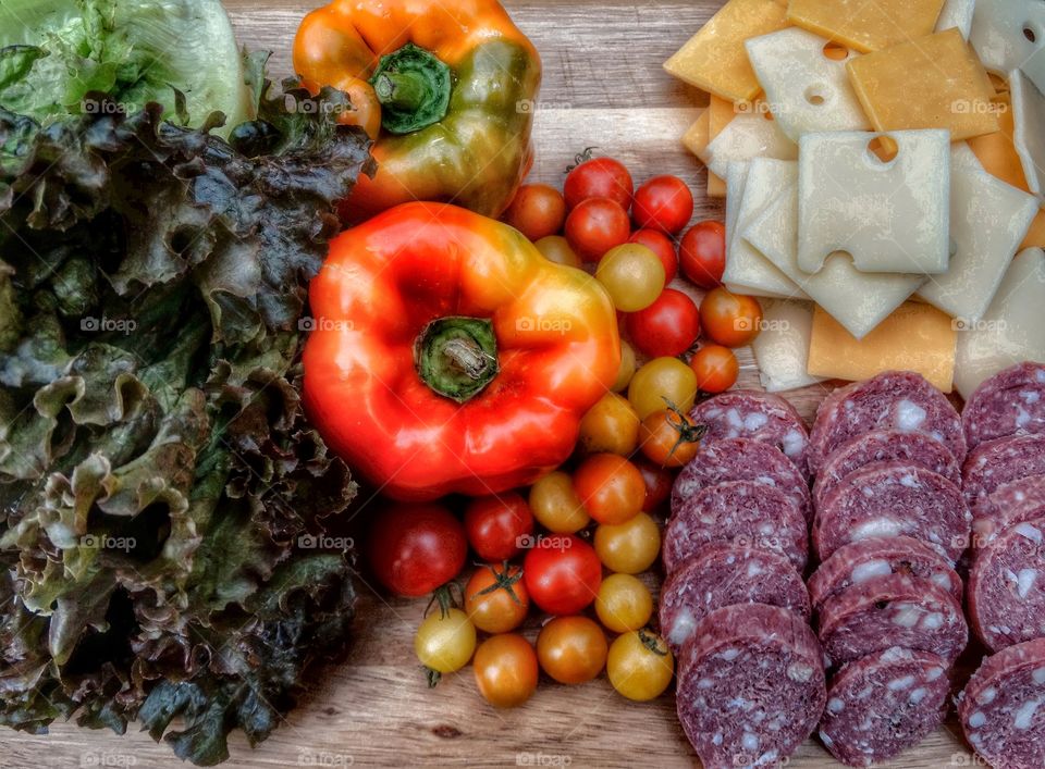 Fresh selection of vegetables, meat, and cheese for a picnic