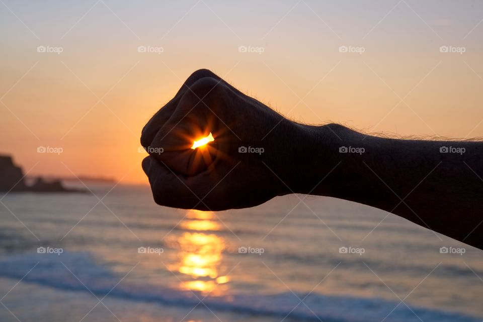 The sun through a fist at sunset 