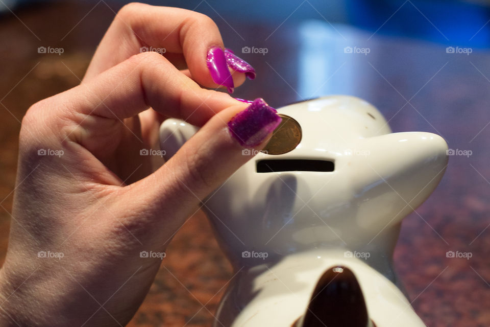 Woman dropping coin into piggy bank