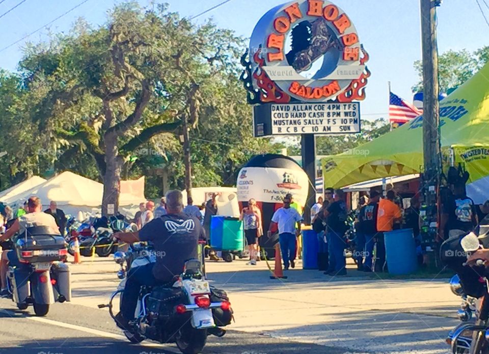 Motorcyclists in Daytona Beach and Ormond Beach Florida during Biketoberfest biker festival. Driving past Iron Horse Saloon, a bar on US Highway 1.  men and women riding Harley Davidson, Honda, BMW motorbikes, trikes and 3-wheelers. 