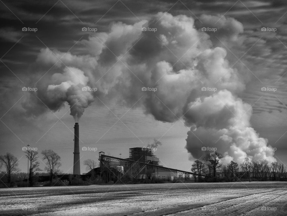 Black and white image of steam and emissions rising from coal and gas fired power plants on cloudy winter day