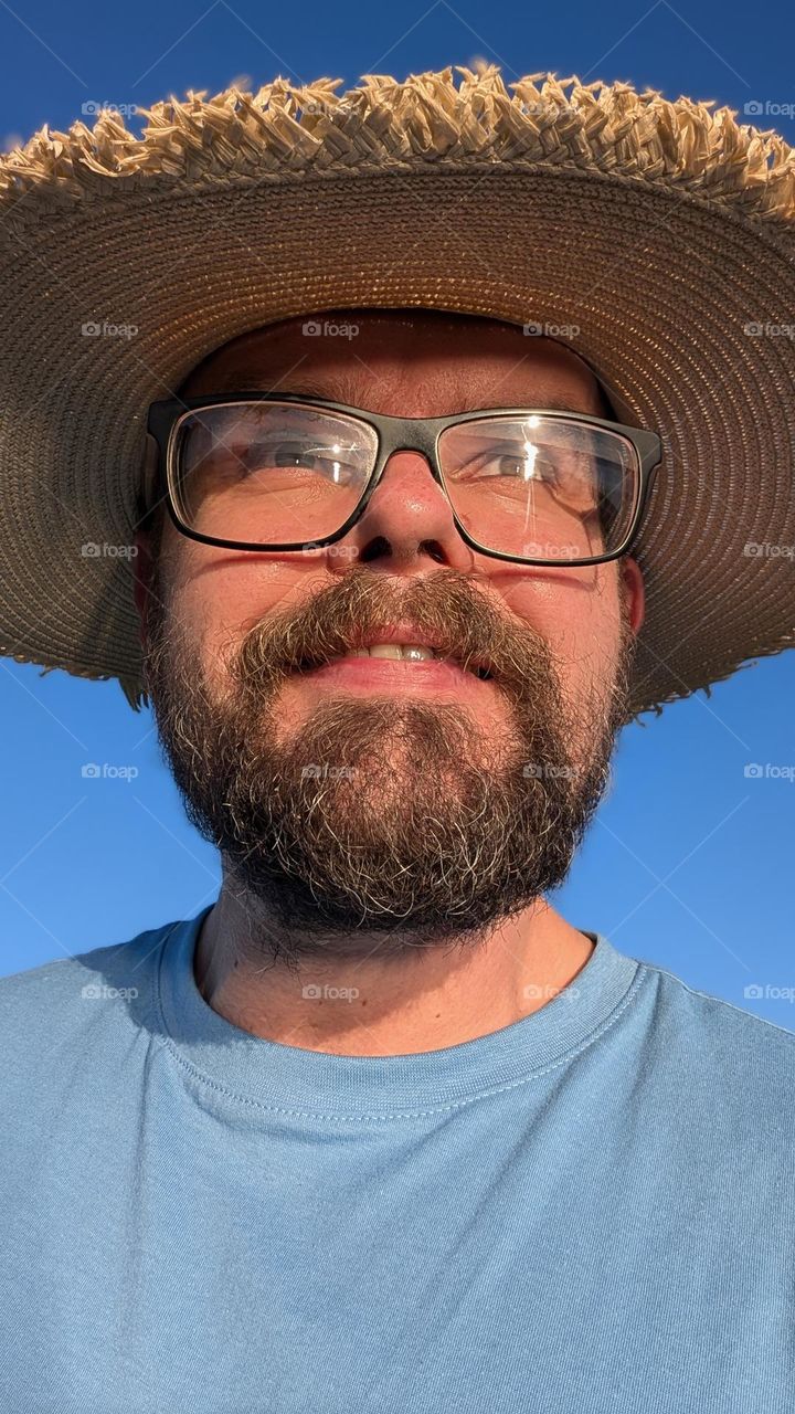 Portrait of bearded man with glasses and straw hat