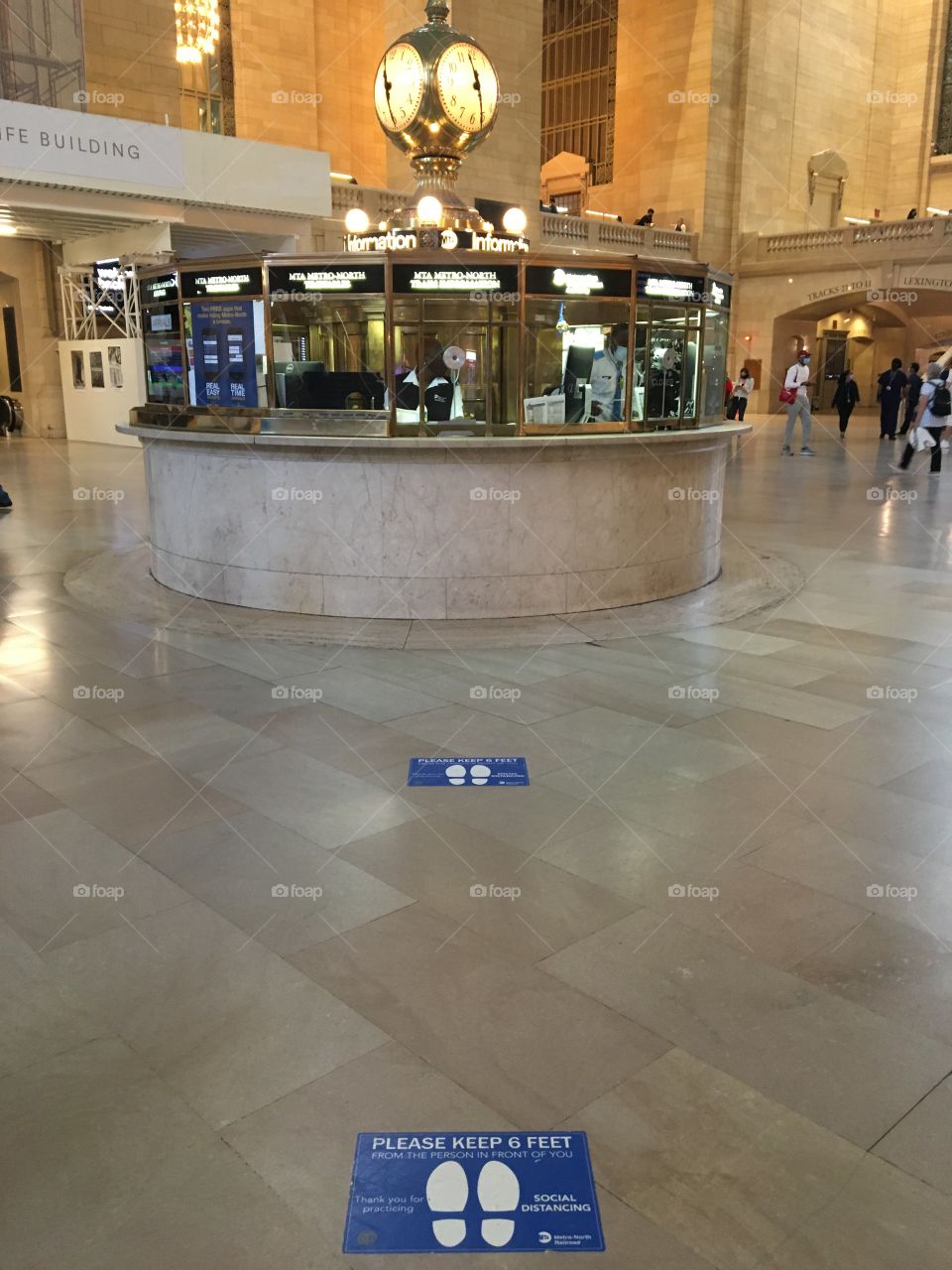 Quiet main hub at Grand Central Terminal in New York City in May (2021) with shoeprint signs on floor asking “please keep 6 feet” apart