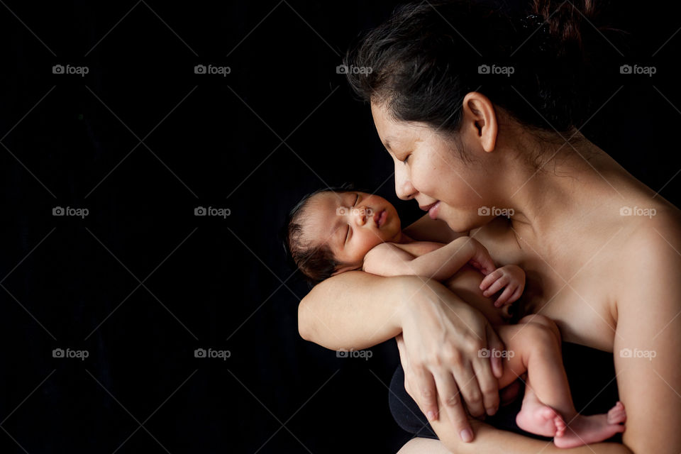 Mother carrying baby against black background