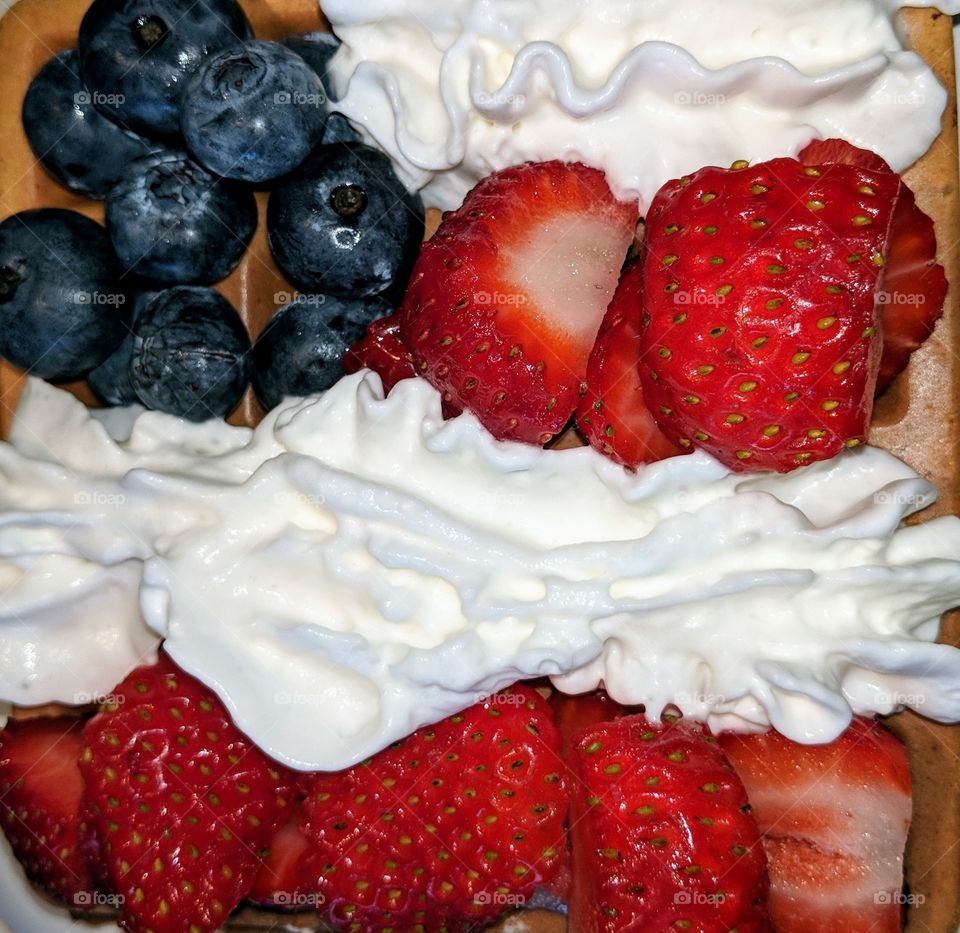 Fourth of July waffle with fruit and whipped cream on it