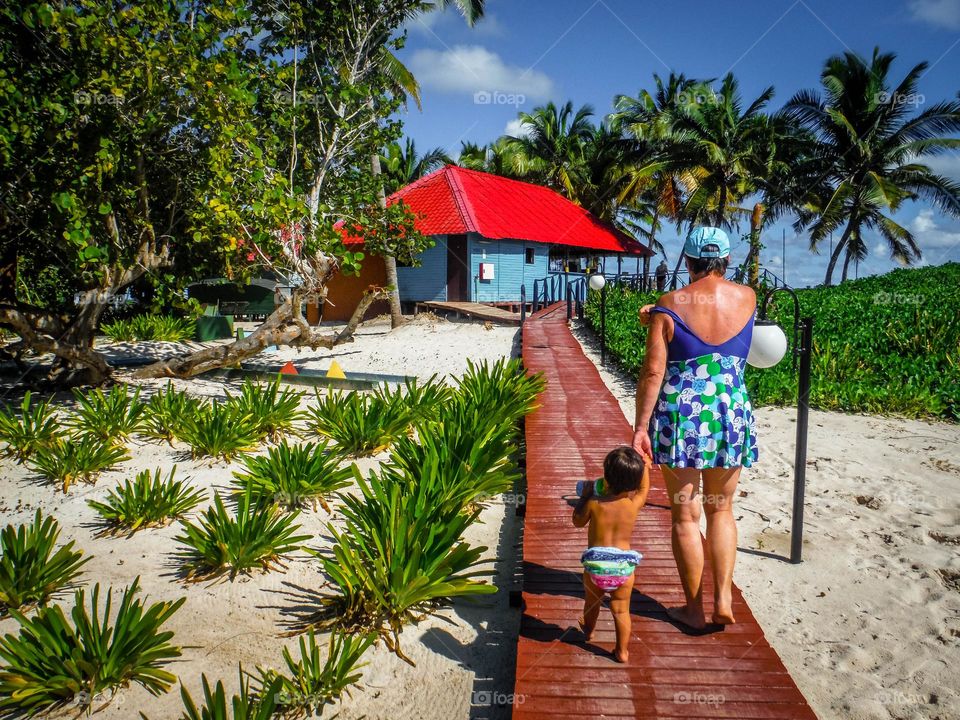 Woman and toddler are walking on a beach