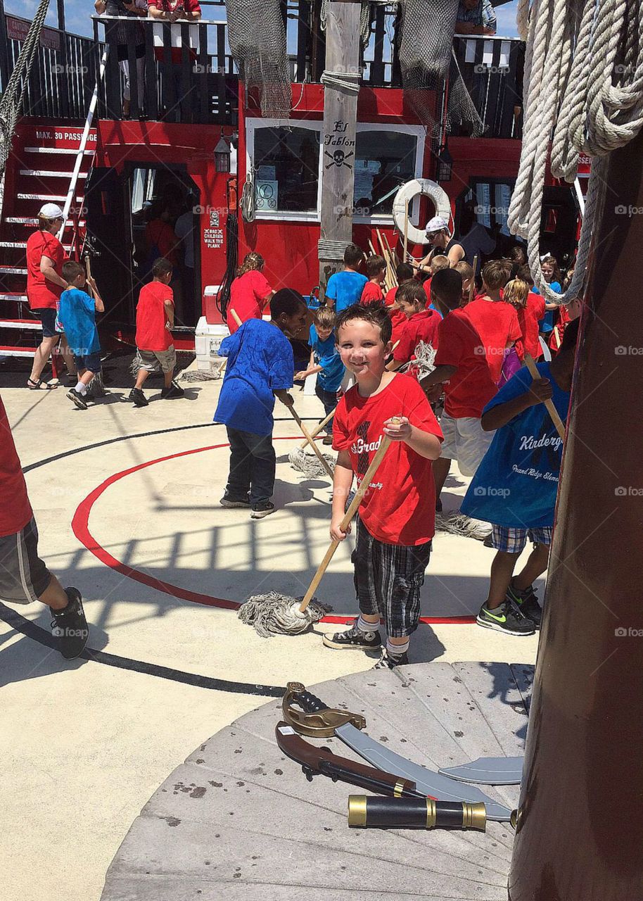 Group of children cleaning with broom in ship