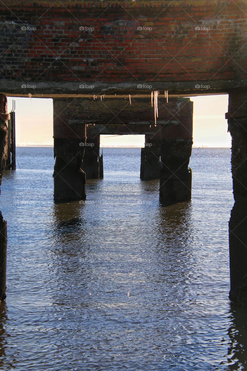 Icicles hanging from an old brick bridge on the North Sea 