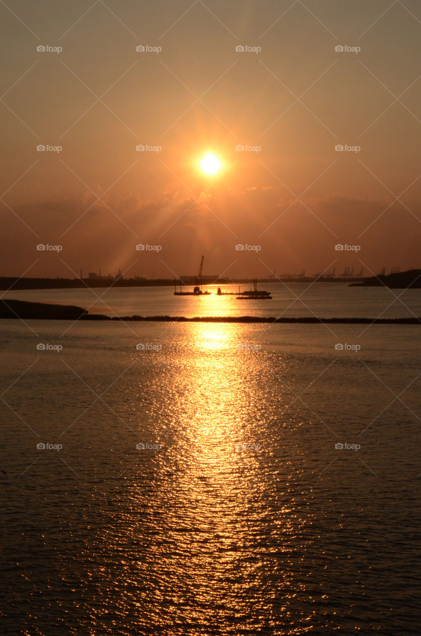 On a river boat cruise that winds down the Savannah river of Georgia a beautiful sunset descends upon the evening sky.